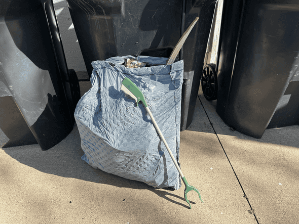 A bag of trash I picked up from around my neighborhood, with the garbage
grabber I got leaning on top of it